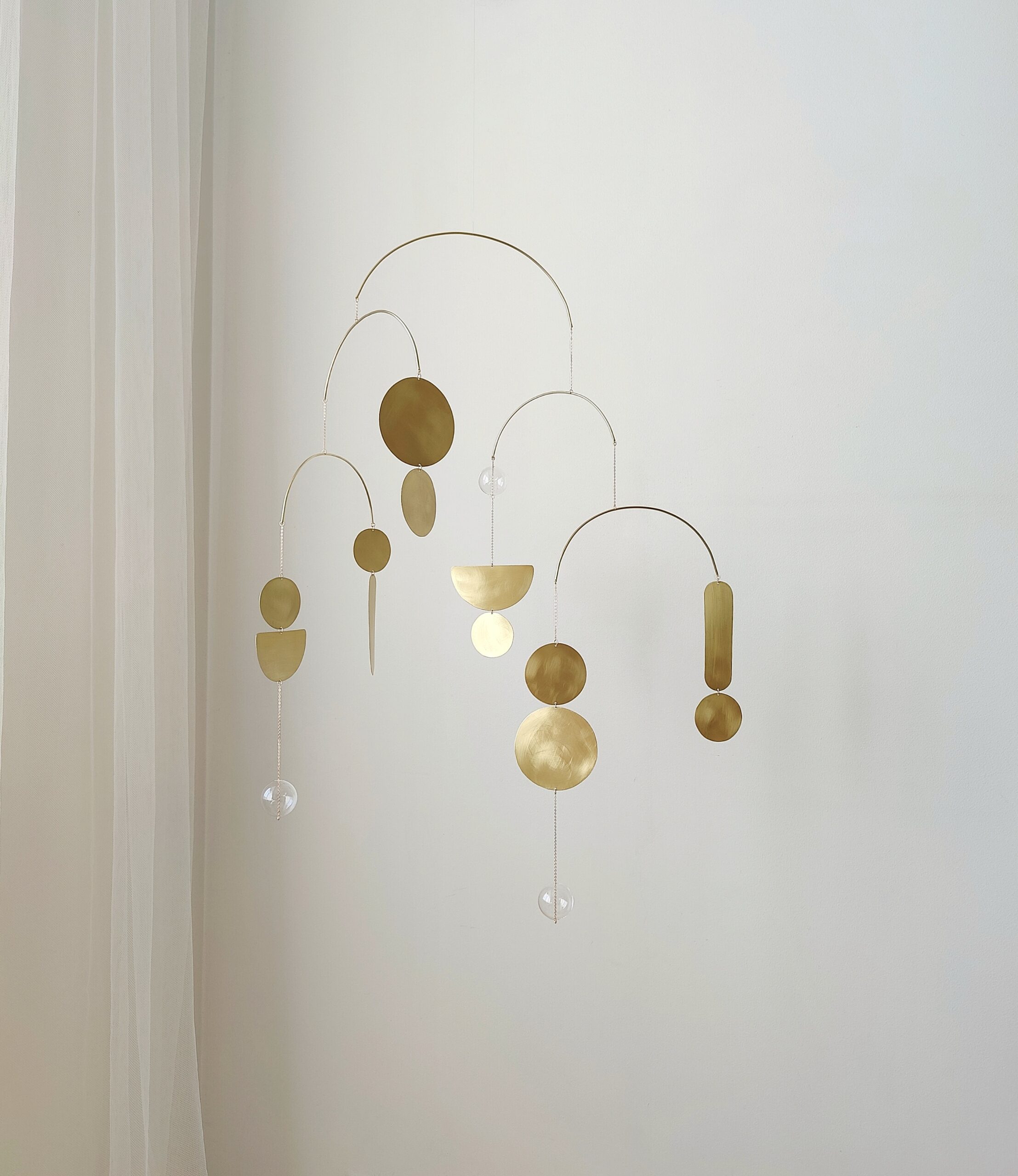 Handmade gold mobile with brass and glass elements casting soft shadows – minimalist boho wall hanging decor