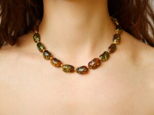 A brown-colored necklace on a woman's neck made with organic beans painted with yellow splashes and coated with glossy resin. this piece blends rustic charm with modern minimalist design.